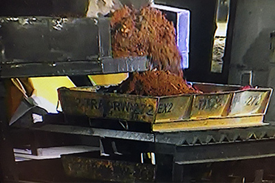 An excavator empties the contents of a sludge drum into a sorting tray at the Accelerated Retrieval Project VII facility